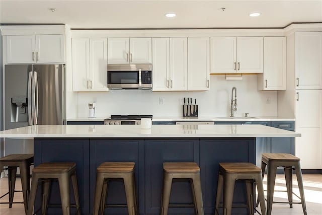 243 Sportsmans Ave, Freeport, NY 11520 - kitchen featuring stainless steel appliances, a kitchen island, white cabinetry, and a breakfast bar area