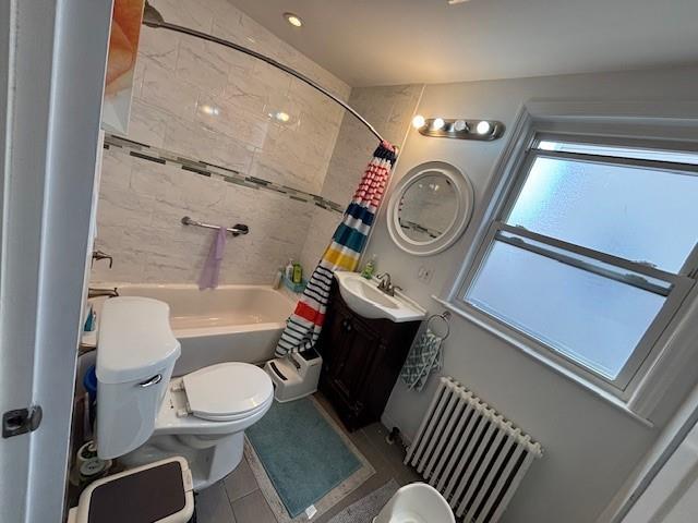 bathroom with toilet, shower / bath combo with shower curtain, vanity, and radiator