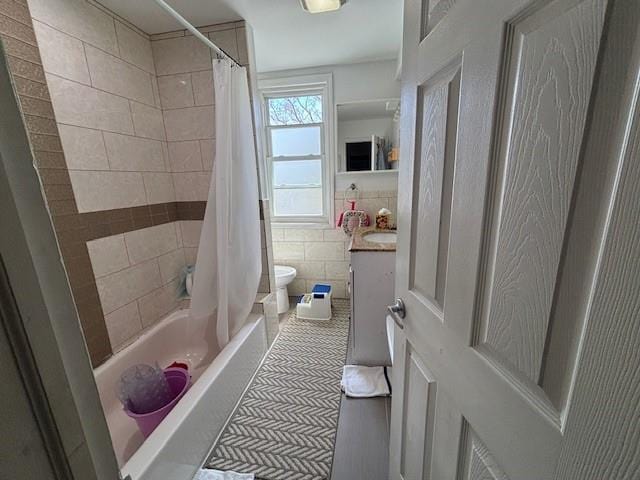 bathroom with shower / tub combo with curtain, tile walls, toilet, and vanity