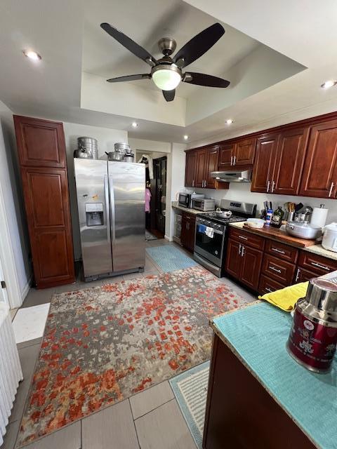 kitchen with stainless steel appliances, recessed lighting, ceiling fan, under cabinet range hood, and a raised ceiling