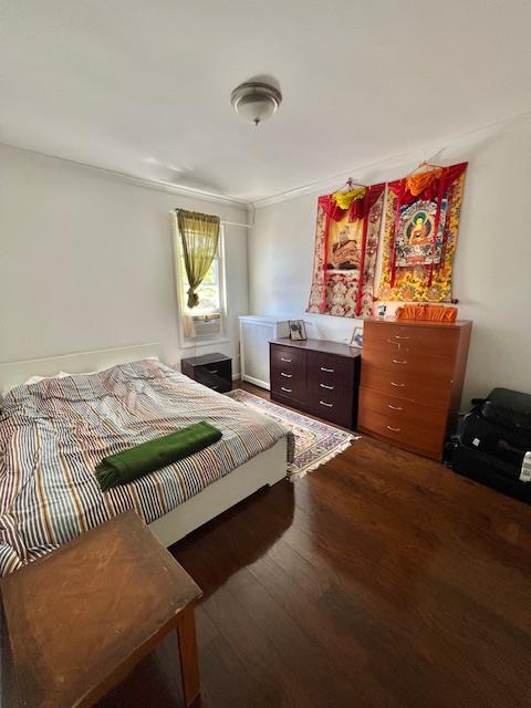 bedroom with dark wood finished floors and crown molding