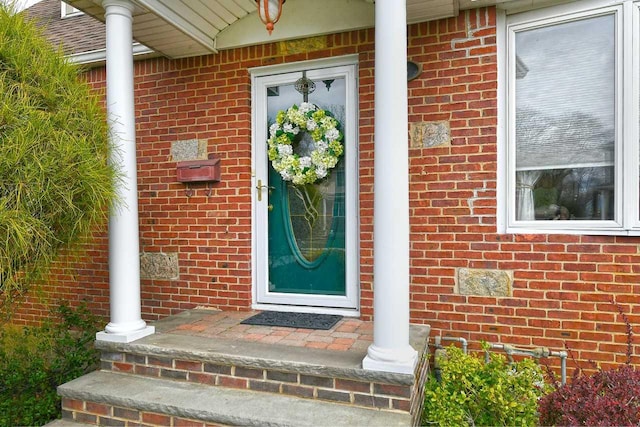 entrance to property with covered porch and brick siding