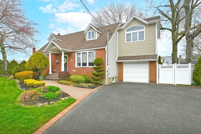view of front of home featuring brick siding, a shingled roof, fence, and aphalt driveway