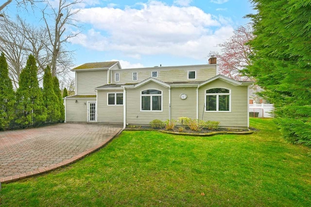 rear view of property with a chimney, fence, and a yard