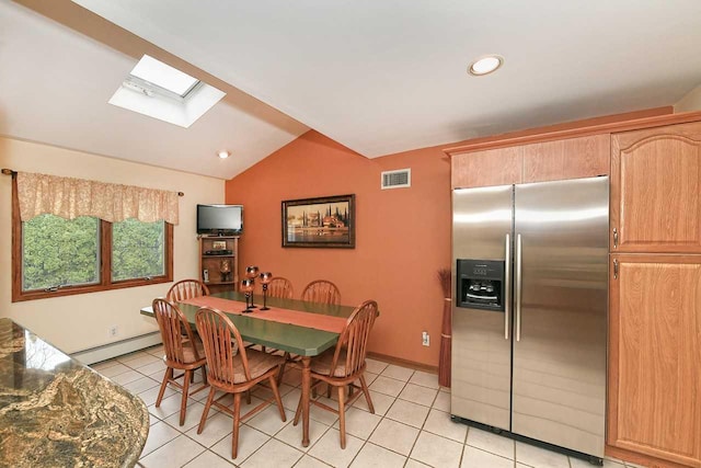 dining room featuring a baseboard heating unit, visible vents, lofted ceiling with skylight, and light tile patterned floors