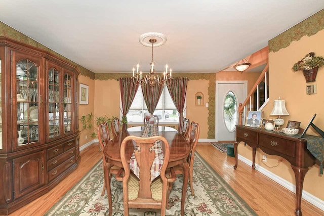 dining area with a chandelier, light wood-type flooring, stairs, and baseboards