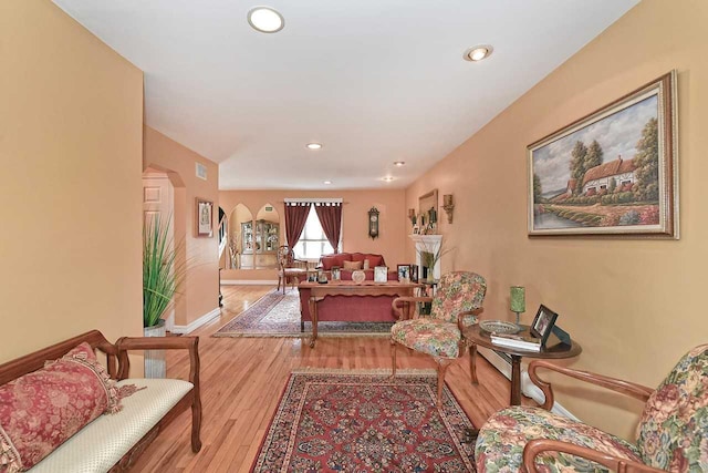 living room with recessed lighting, wood finished floors, arched walkways, and baseboards