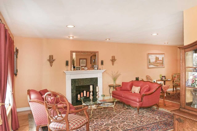 living area featuring baseboards, recessed lighting, wood finished floors, and a fireplace