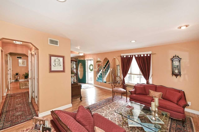 living area featuring recessed lighting, wood finished floors, visible vents, arched walkways, and baseboards