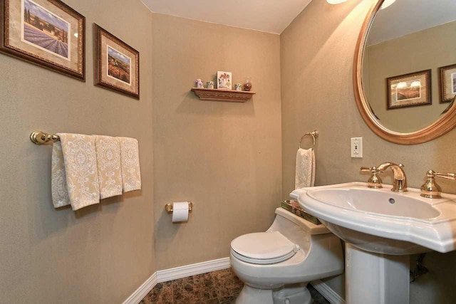 bathroom featuring toilet and baseboards
