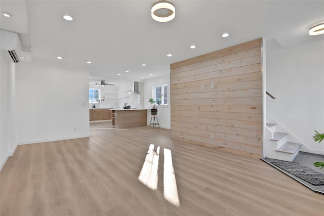 unfurnished living room with recessed lighting, a wall mounted AC, and light wood finished floors