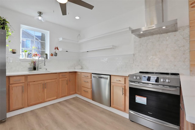 kitchen with a sink, stainless steel appliances, light wood finished floors, backsplash, and wall chimney exhaust hood