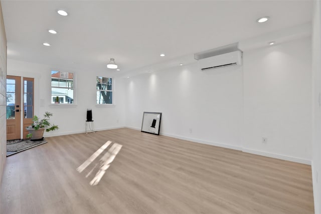 exercise room featuring recessed lighting, light wood-type flooring, baseboards, and a wall mounted air conditioner
