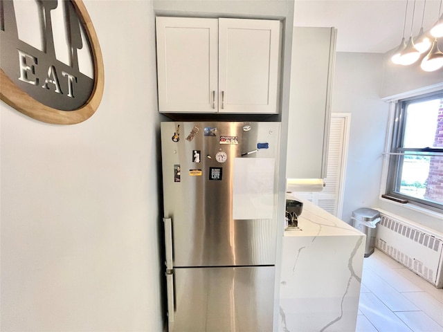 61-20 Grand Central Pkwy Unit A1503, Forest Hills, NY 11375 - kitchen featuring radiator heating unit, tile patterned flooring, freestanding refrigerator, light stone countertops, and white cabinetry
