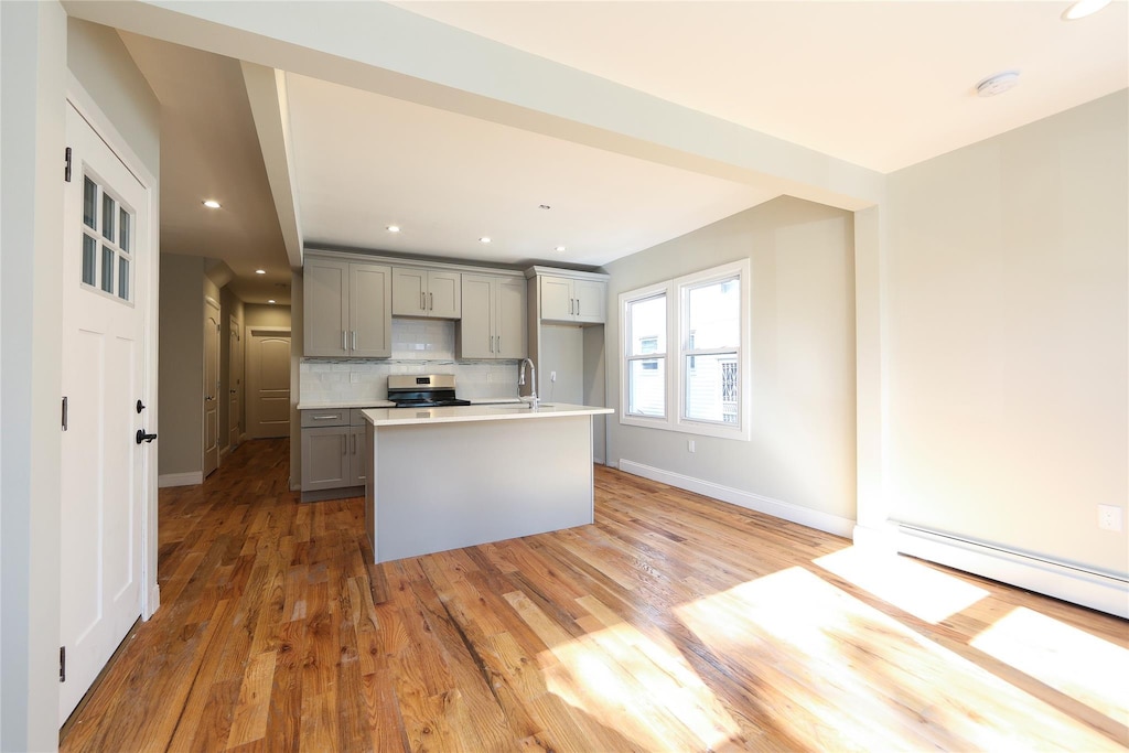 24027 Newhall Ave, Rosedale, NY 11422 - kitchen with a sink, decorative backsplash, stainless steel electric range, light wood-style floors, and gray cabinetry