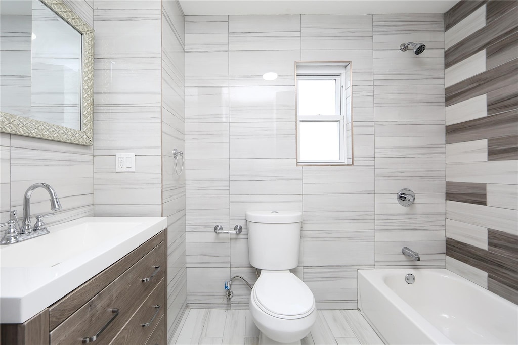 24027 Newhall Ave, Rosedale, NY 11422 - full bathroom with toilet, vanity, washtub / shower combination, and tile walls