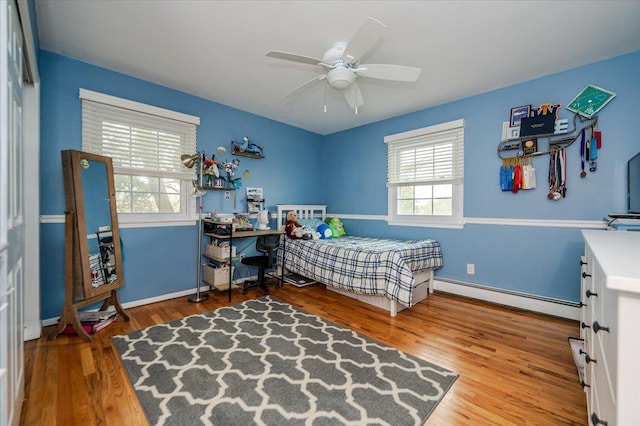 bedroom featuring a baseboard radiator, wood finished floors, a ceiling fan, and baseboards