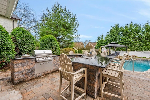 view of patio / terrace with area for grilling, exterior kitchen, a gazebo, a bar, and a fenced backyard