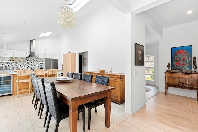 211 Red Dirt Rd, East Hampton, NY 11937 - dining room with high vaulted ceiling, beverage cooler, light wood-type flooring, an inviting chandelier, and baseboards