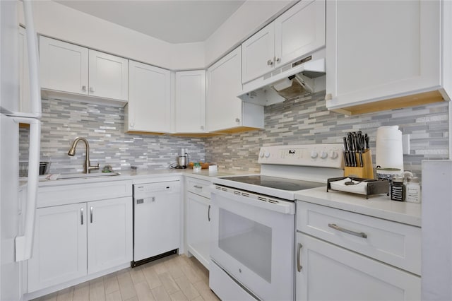 kitchen with light countertops, a sink, under cabinet range hood, and white appliances