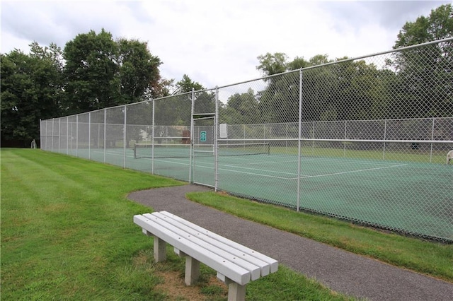 view of sport court featuring fence and a lawn