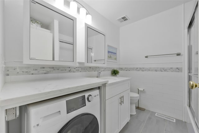 bathroom featuring toilet, washer / dryer, visible vents, and vanity