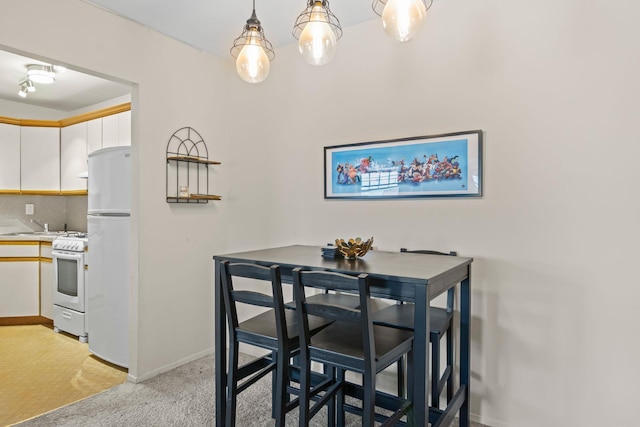 dining area featuring baseboards and light colored carpet