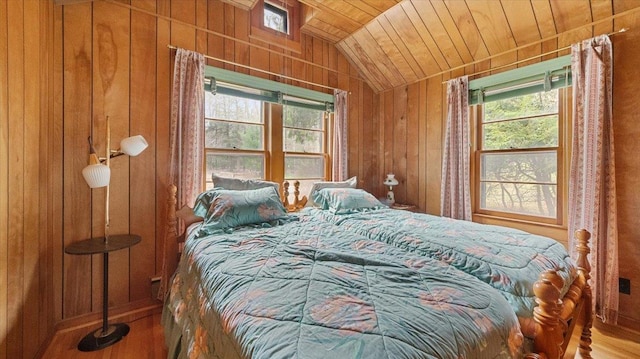 bedroom featuring vaulted ceiling, wood walls, wooden ceiling, and wood finished floors