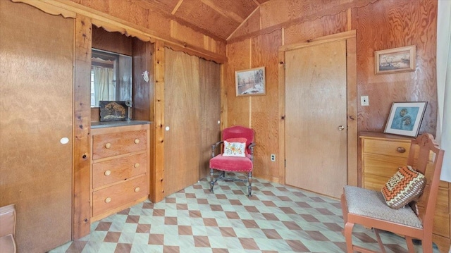 sitting room with light floors, wooden walls, and lofted ceiling