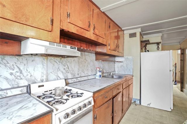 kitchen with a sink, tasteful backsplash, under cabinet range hood, and white appliances
