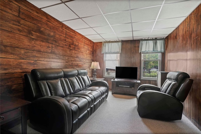 living area with wooden walls, carpet floors, and a drop ceiling