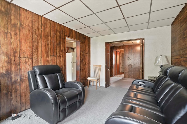 carpeted living room featuring a paneled ceiling and wooden walls