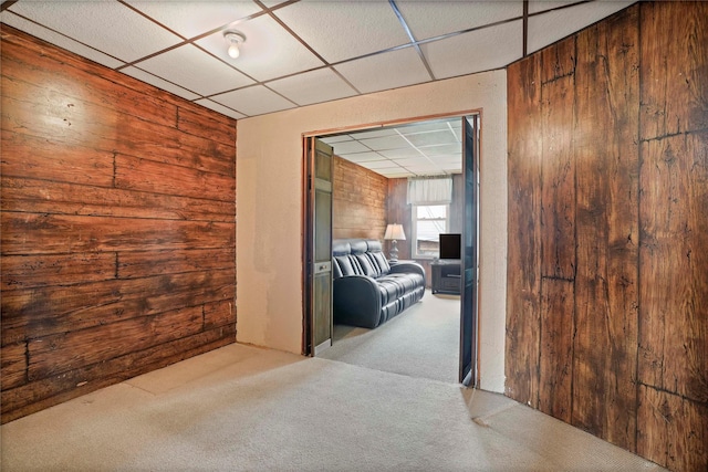 interior space with a drop ceiling and wooden walls