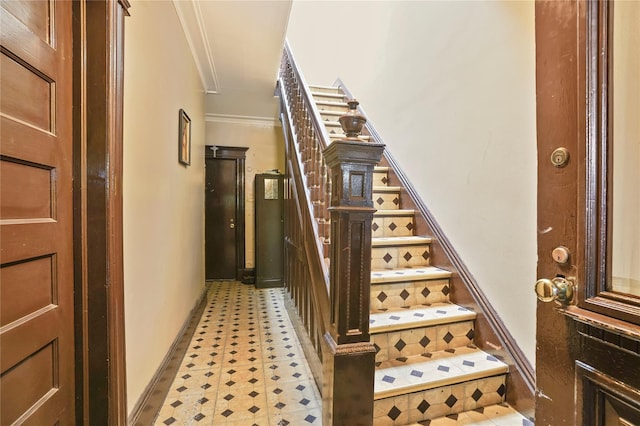 staircase featuring baseboards, ornamental molding, attic access, and tile patterned floors