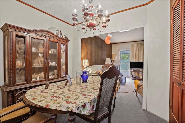 dining room featuring an inviting chandelier, ornamental molding, a textured ceiling, and carpet flooring