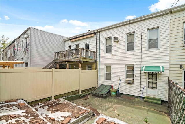 back of house with a fenced backyard, a wall mounted AC, and cooling unit
