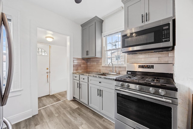 69-06 79th St, Middle Village, NY 11379 - kitchen featuring stainless steel appliances, a sink, tasteful backsplash, light wood-type flooring, and gray cabinetry
