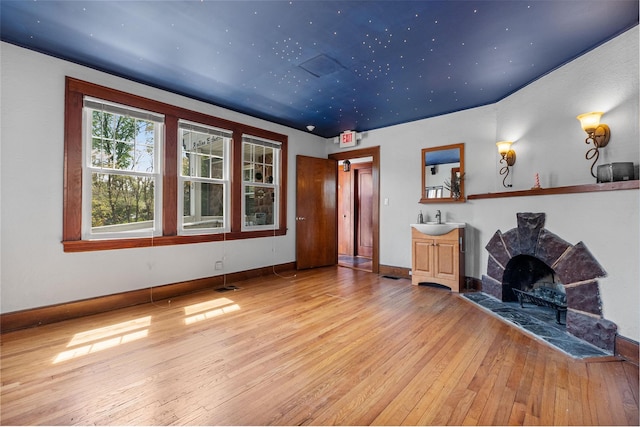 unfurnished living room with baseboards, hardwood / wood-style floors, visible vents, and a sink