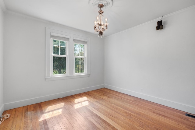 unfurnished room featuring a notable chandelier, light wood finished floors, baseboards, ornamental molding, and visible vents