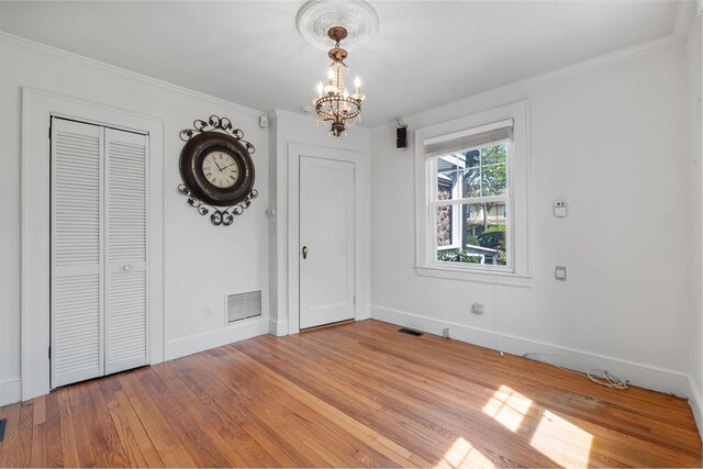 unfurnished dining area featuring light wood-type flooring, visible vents, crown molding, and an inviting chandelier