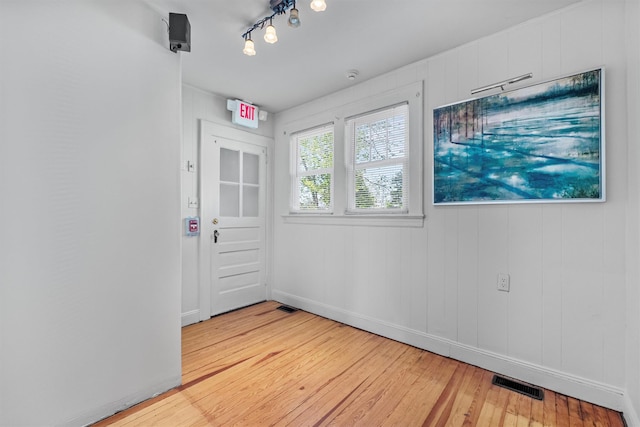 unfurnished room with light wood-style flooring, visible vents, and baseboards