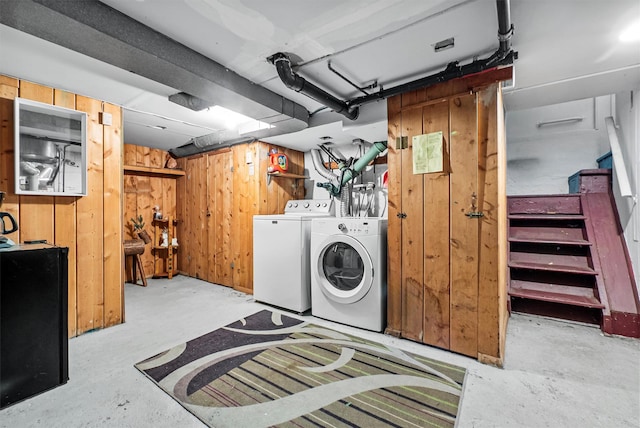washroom featuring separate washer and dryer, wooden walls, and laundry area
