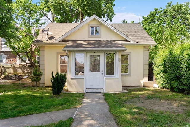 45 Dehnhoff Ave, Freeport, NY 11520 - bungalow-style house with fence, a shingled roof, a front lawn, and stucco siding