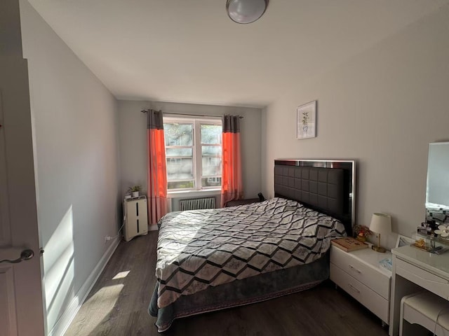 bedroom featuring baseboards, dark wood-style flooring, and radiator heating unit