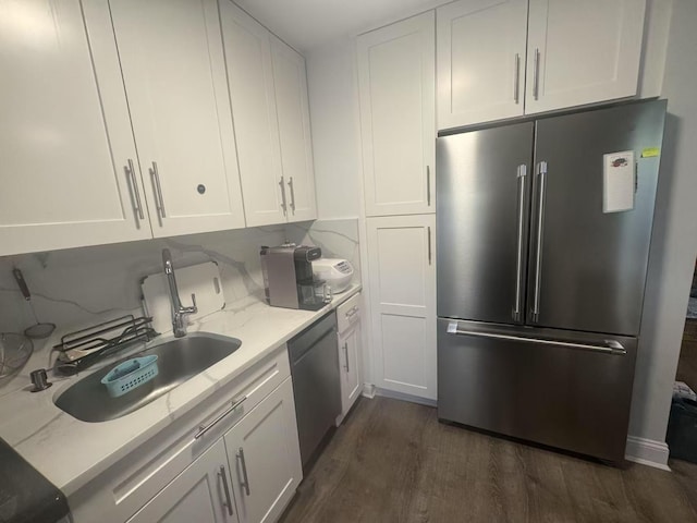 kitchen with dark wood-style floors, white cabinetry, light stone counters, a sink, and stainless steel appliances