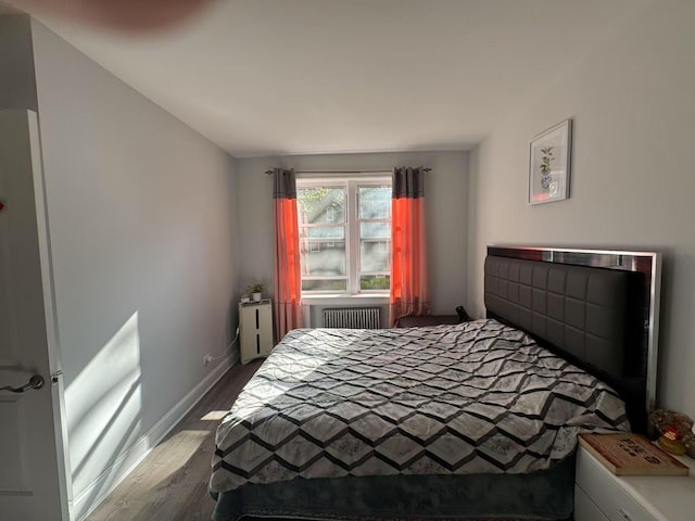 bedroom with radiator, baseboards, and wood finished floors