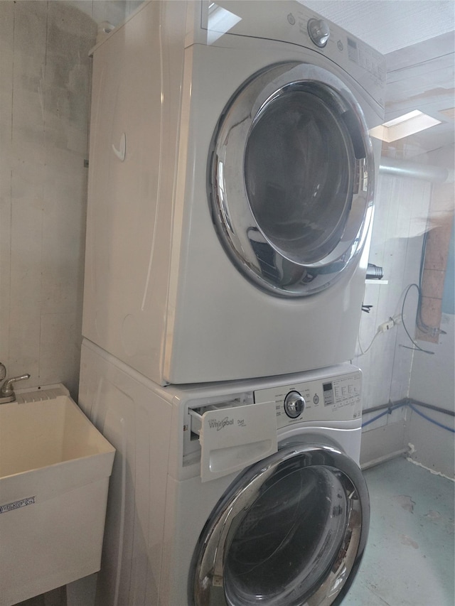 clothes washing area with stacked washer and dryer and a sink