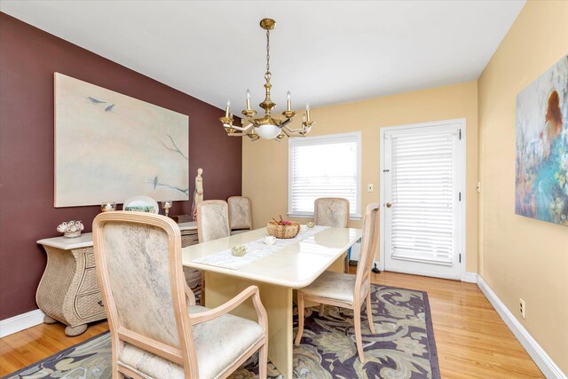 dining room with baseboards, a notable chandelier, and light wood finished floors