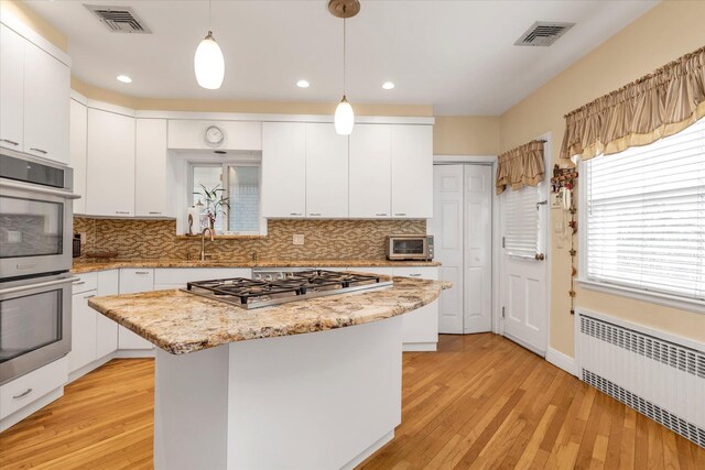 kitchen featuring radiator, visible vents, light wood finished floors, and stainless steel appliances