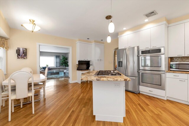 kitchen featuring white cabinets, light wood finished floors, stainless steel appliances, and visible vents